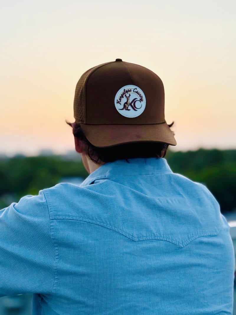Caramel Country hat worn backwards at golden hour, white KC patch catching the sunset
