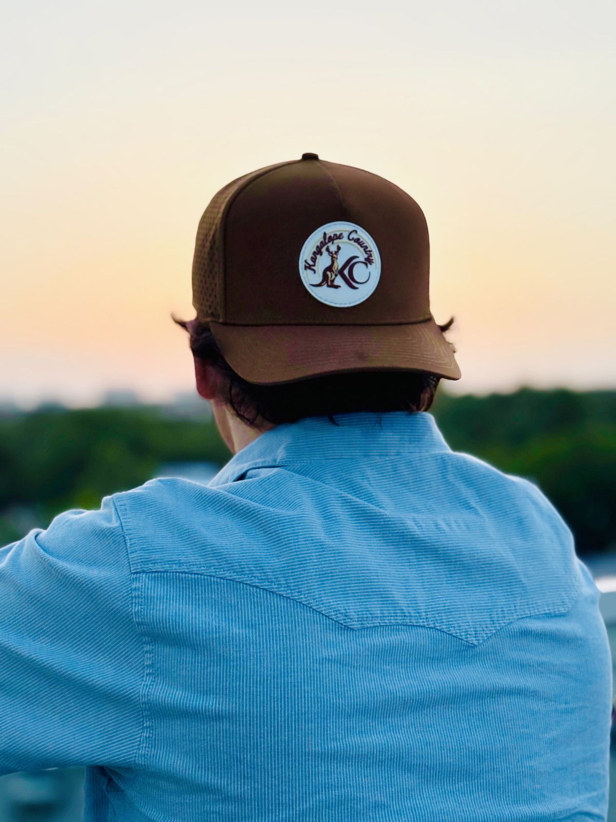 Caramel Country hat worn backwards at golden hour, white KC patch catching the sunset
