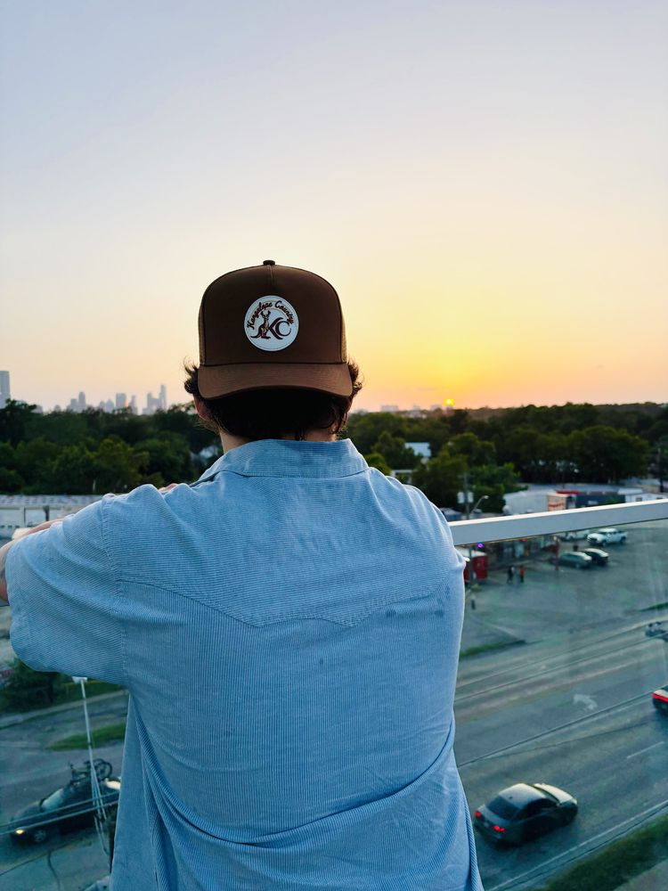 Caramel Country hat worn on a rooftop at sunset over a US city skyline