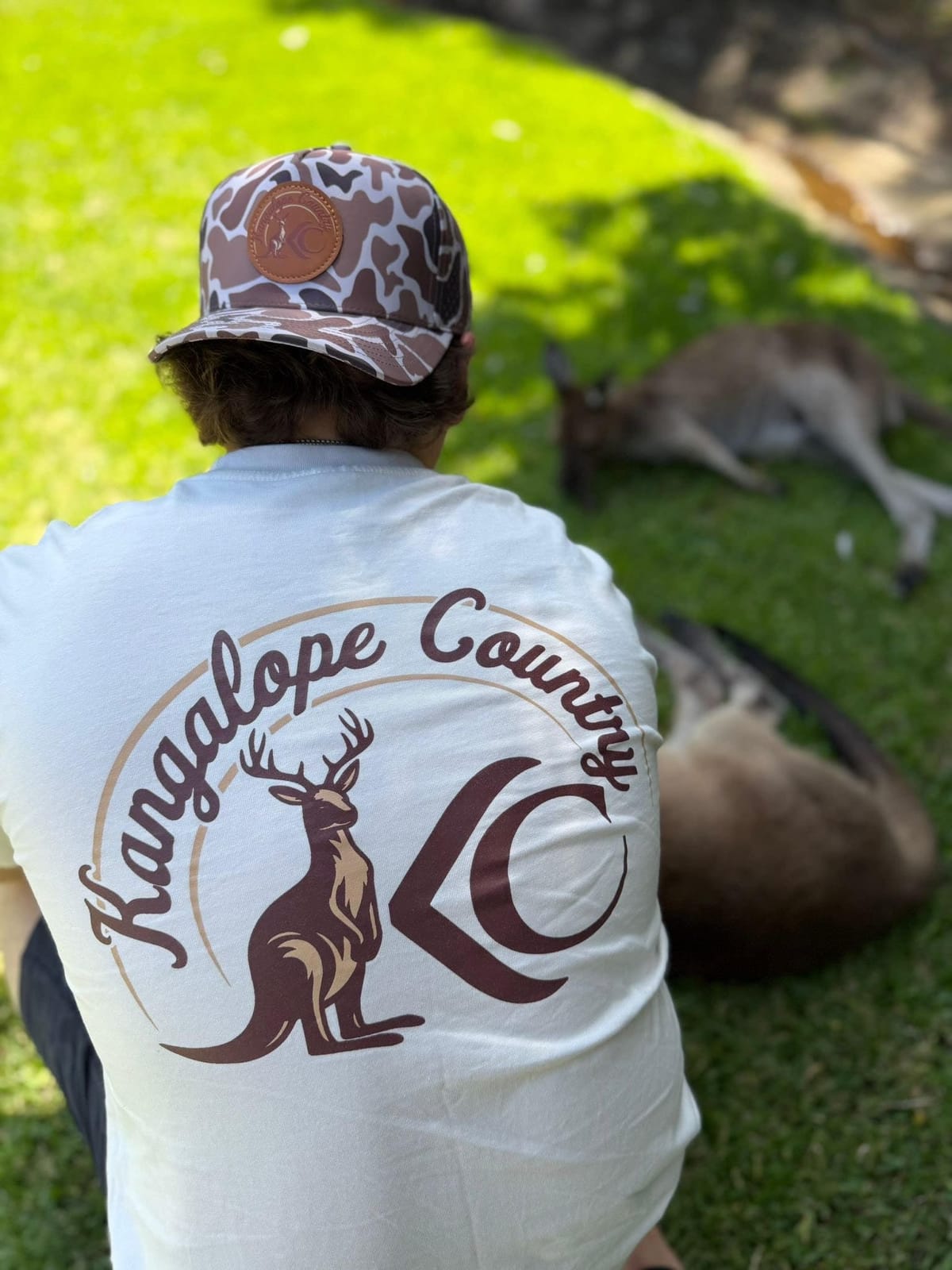 Back print of the Ecru tee worn with the Bush Camo hat, kangaroos lazing on the grass beyond