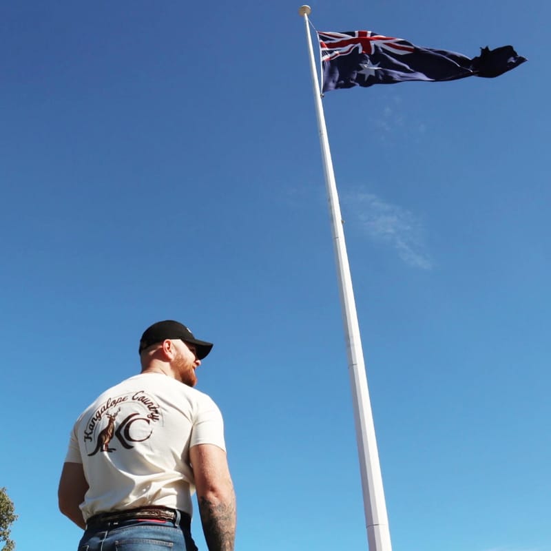 Kangalope Country tee worn while looking up at the Australian flag flying from a tall flagpole
